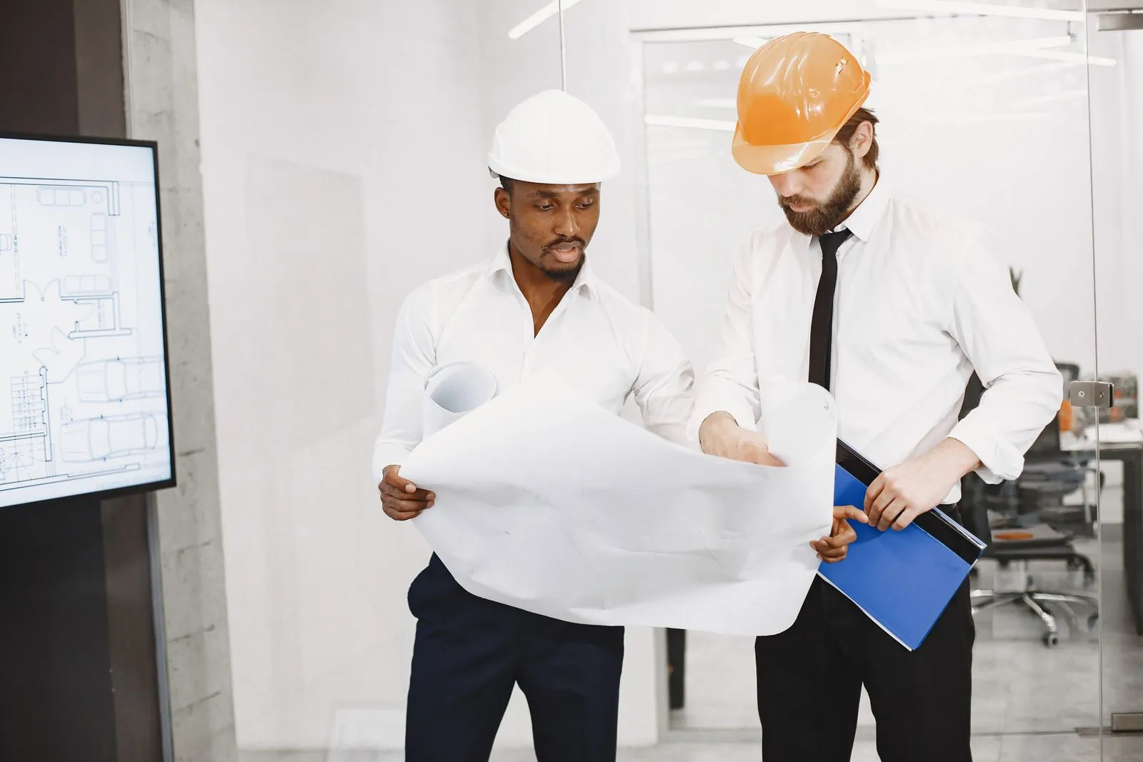Baretli iki mühendis onaylı projeyi inceleyerek eksik işleri kontrol ediyor