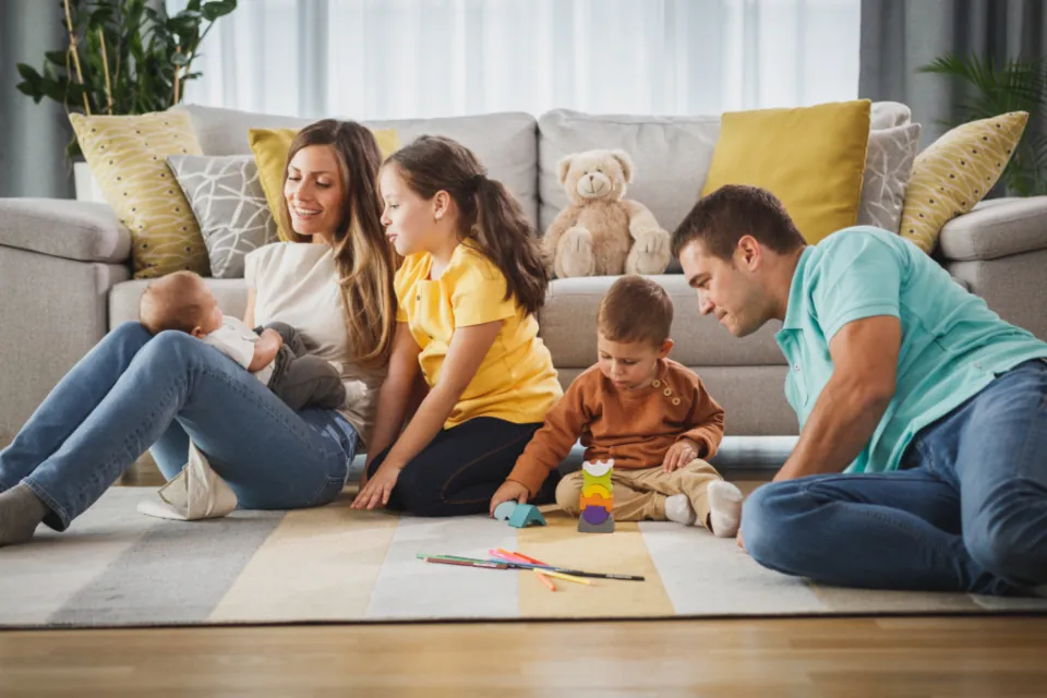 Oturma odasında çocuklarıyla oyun oynayan anne ve baba