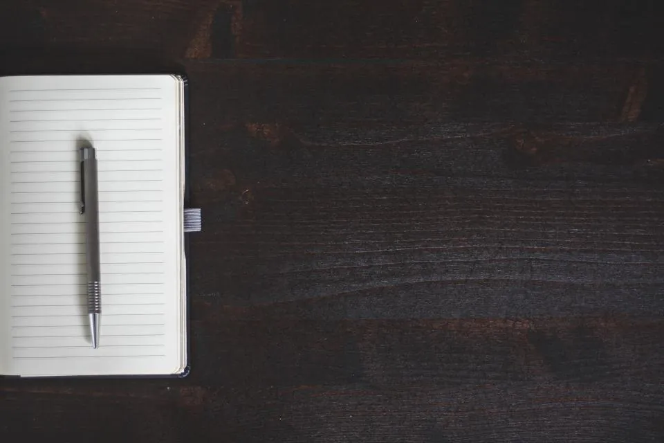 Koyu ahşap masada açık defter ve kalem, idari dava dilekçesi hazırlığı