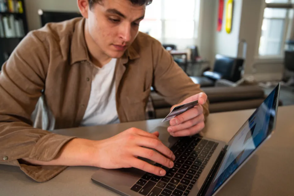 Telefon ve bilgisayarla internet bankacılığı işlemi yapan kişi