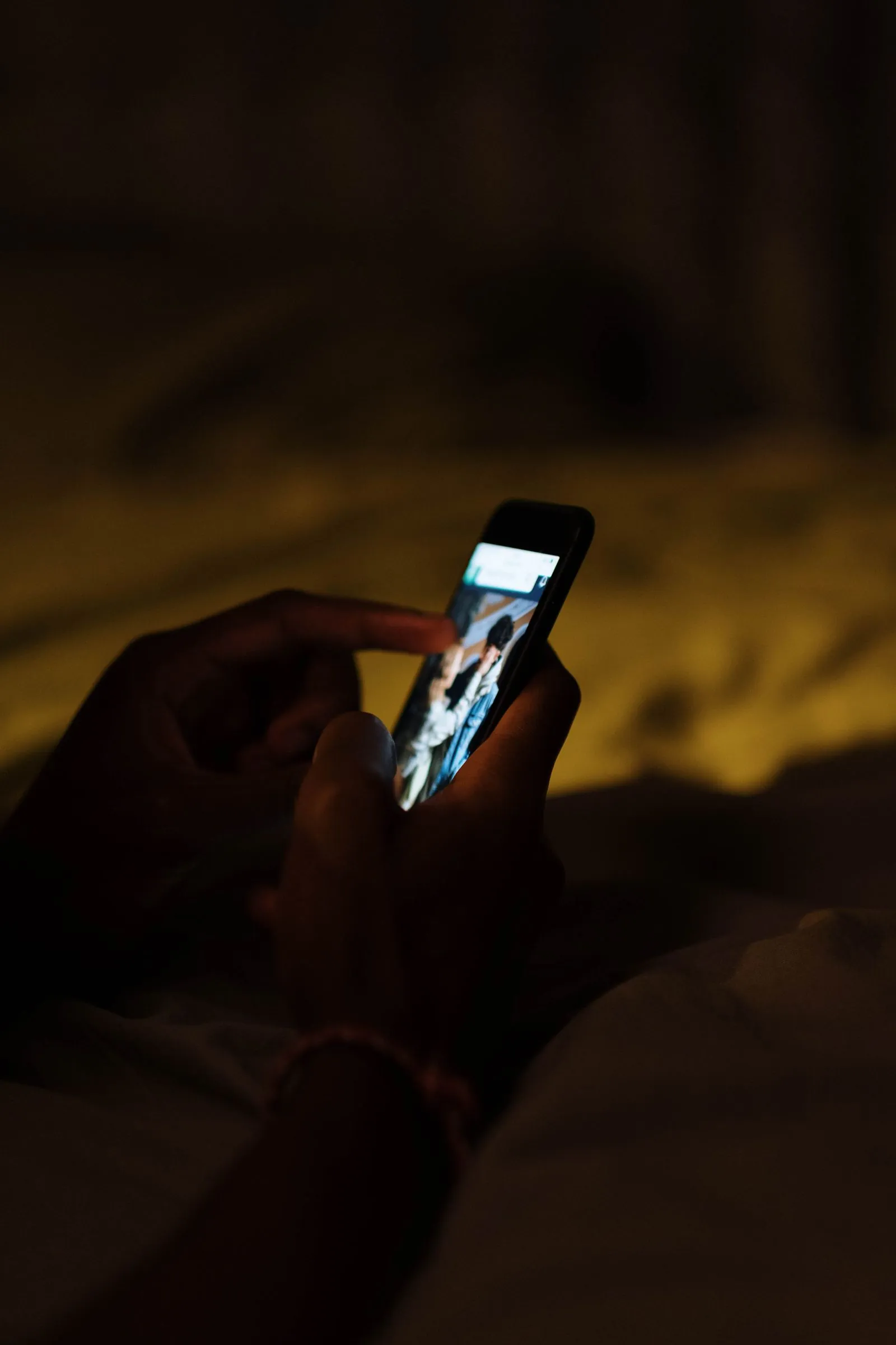 Karanlık odada tehdit mesajı gelen telefonu tutan eller