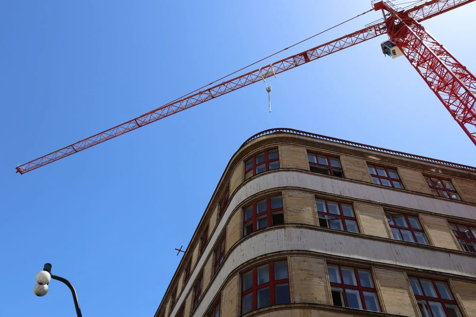 Kavisli cepheli apartman binasının üzerinde yükselen inşaat vinci