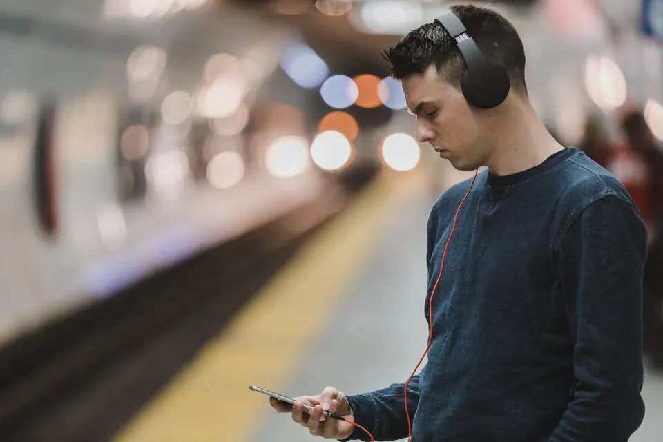 Banliyö treni peronunda telefonuna bakarak treni bekleyen bir yolcu