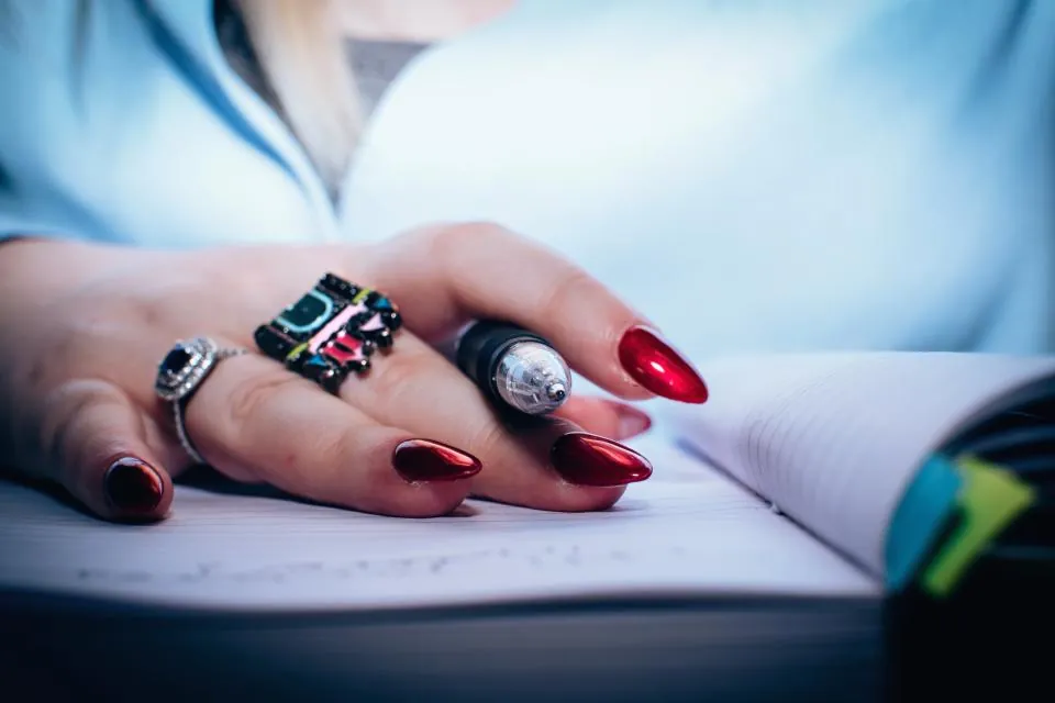 Açık bir defter üzerinde kalem tutarak not almaya hazırlanan el