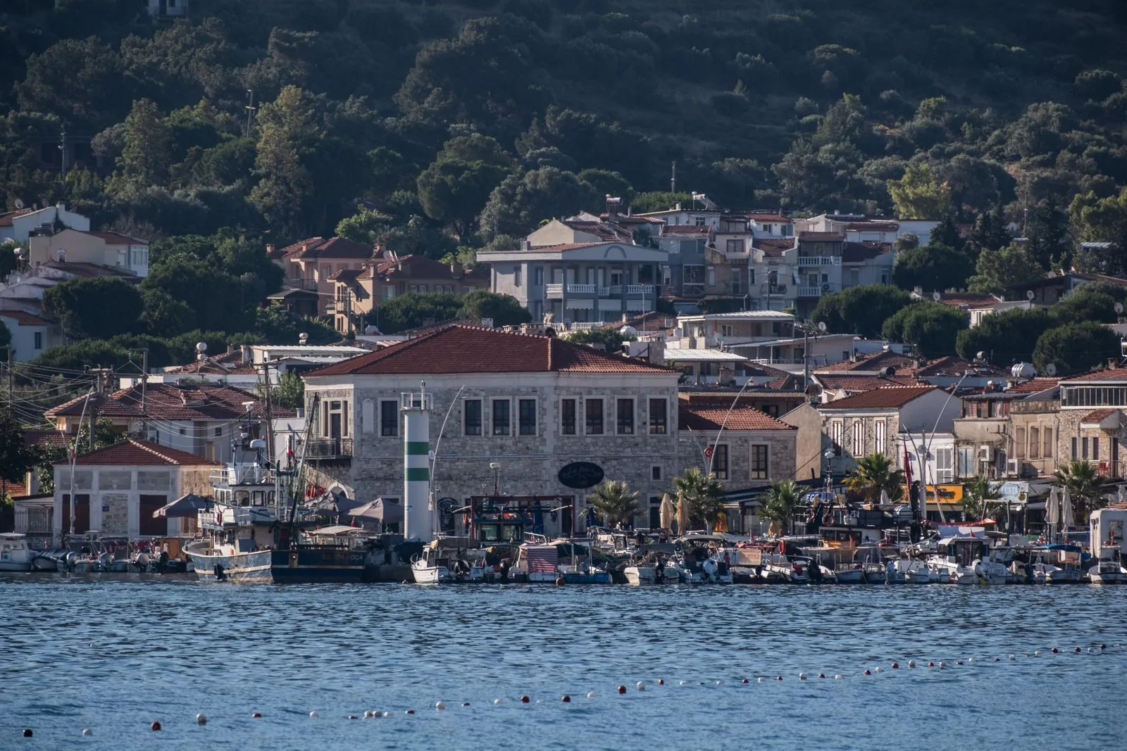 Foça kıyısında taş evler ve teknelerle turizm sezonu manzarası