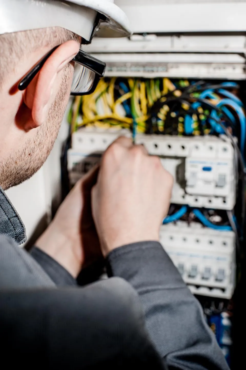 Elektrik panosunda çalışan baretli teknisyen