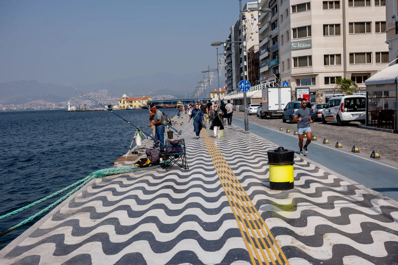 İzmir sahilinde dalgalı desenli yürüyüş yolu ve olta balıkçıları