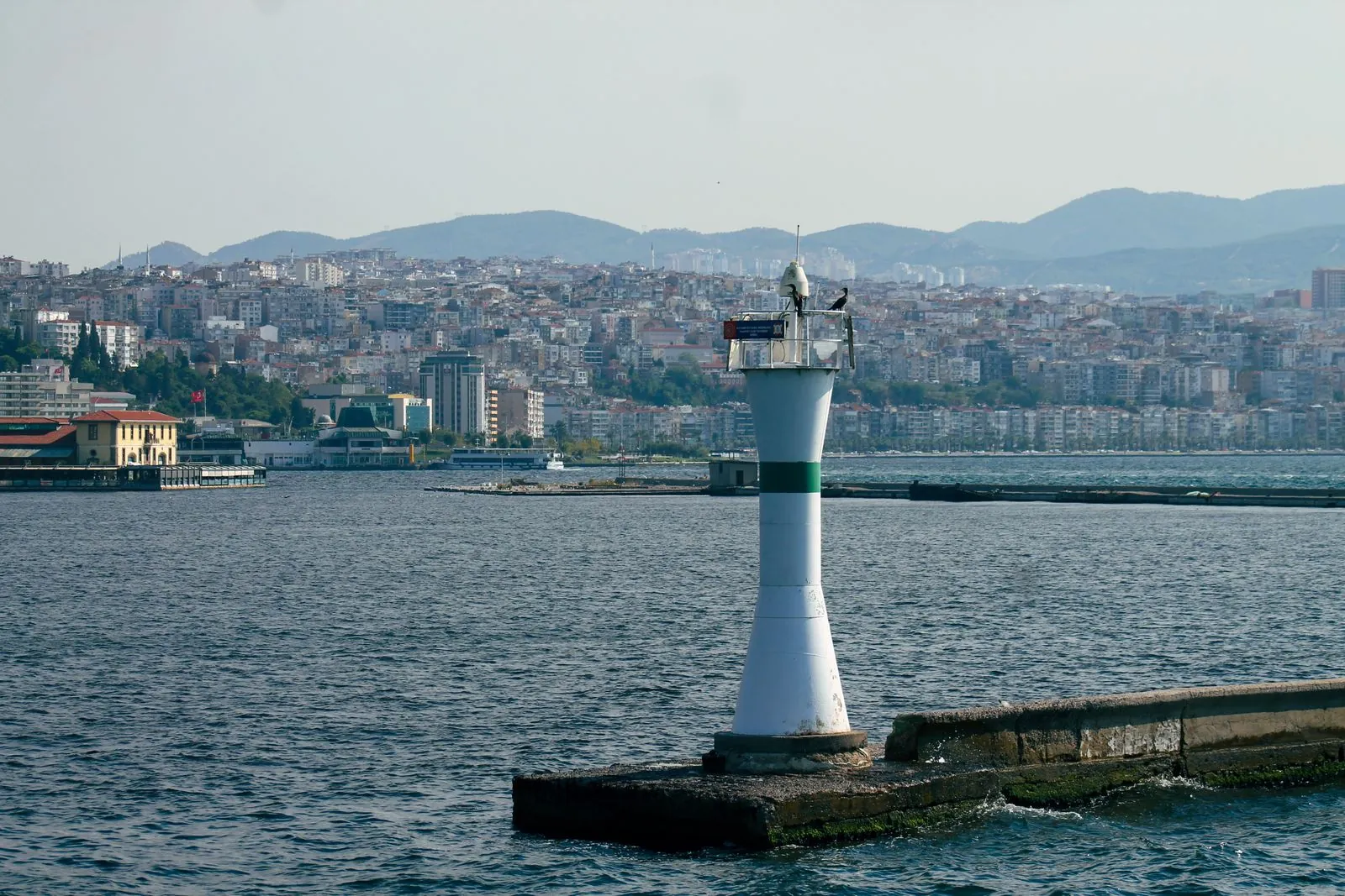 İzmir körfezindeki deniz feneri ve arka planda şehir silueti