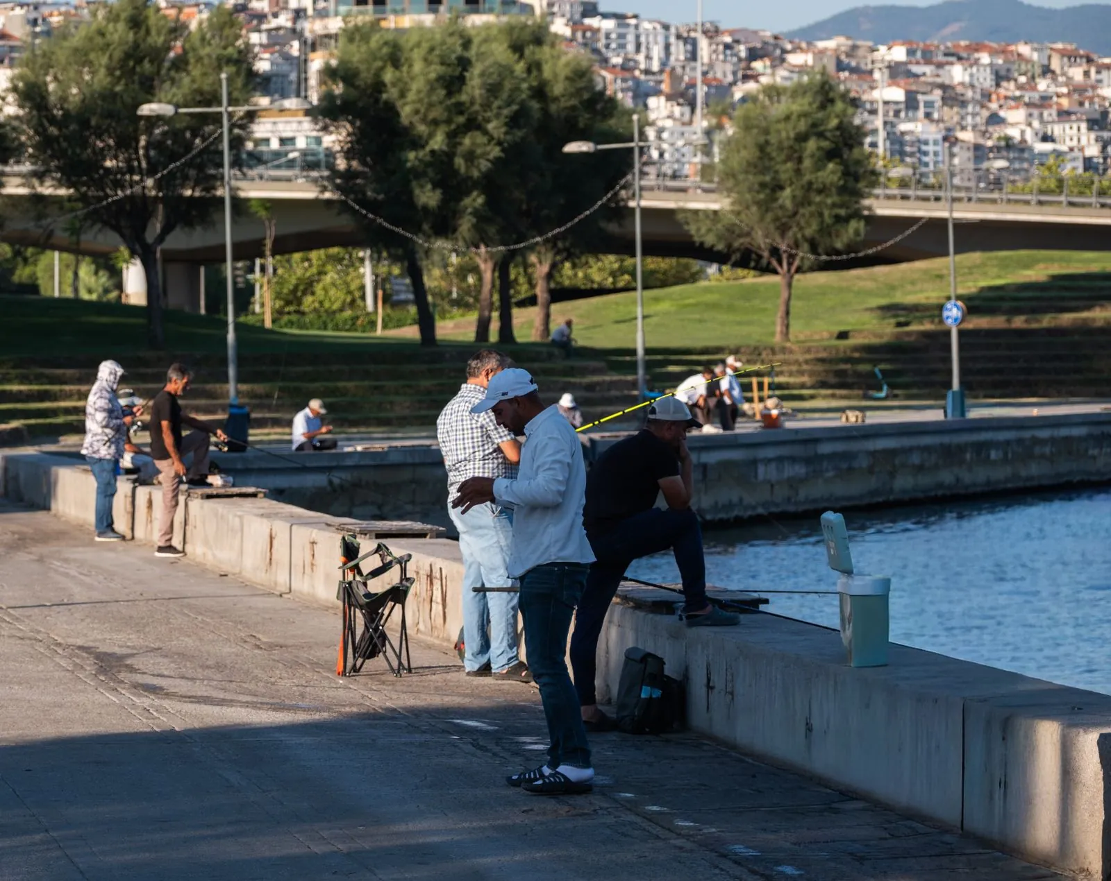 İzmir sahilinde köprü ve yamaçtaki konutlar önünde gündelik yaşam