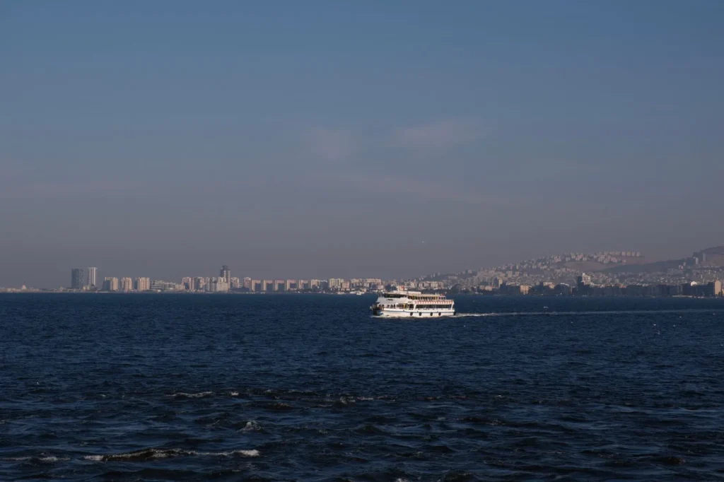 İzmir'de oturma izni reddine itiraz süreci için körfezde ilerleyen vapur ve kent silueti