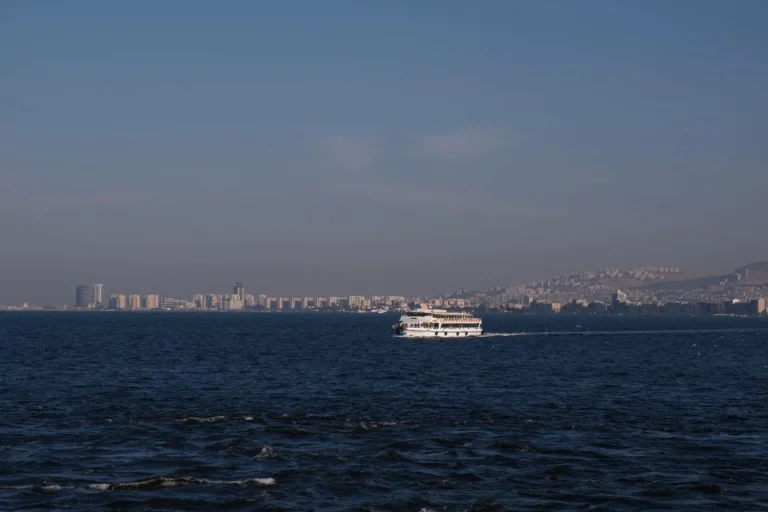 İzmir'de oturma izni reddine itiraz süreci için körfezde ilerleyen vapur ve kent silueti