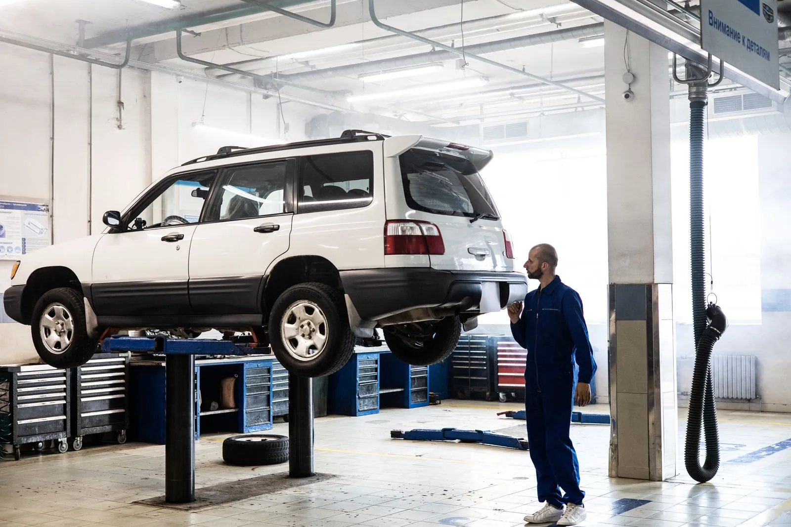 Lifte kaldırılmış aracı inceleyen servis çalışanı