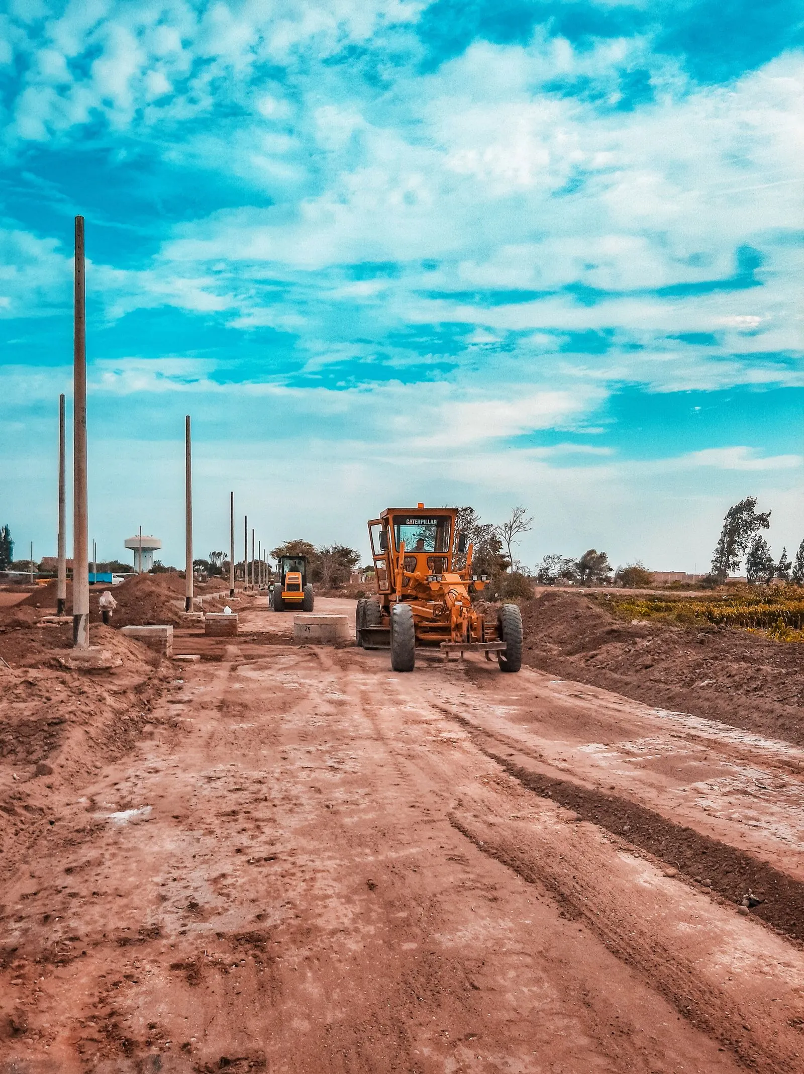 Toprak yolda çalışan greyder, özel arazi üzerinden yol açılmasını anlatan görsel